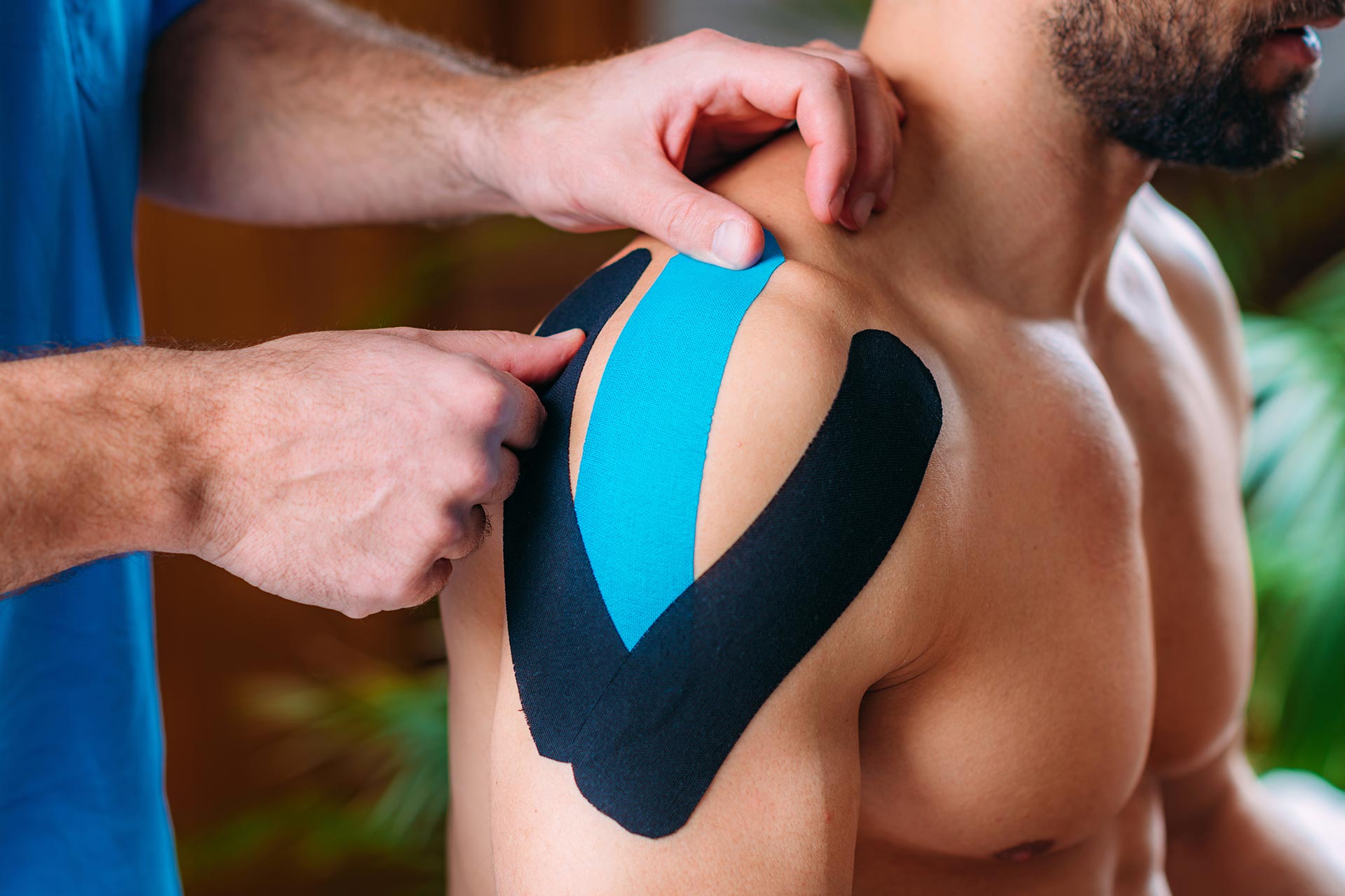 therapist-taping-mans-shoulder-with-elastic-therap-354AXBL